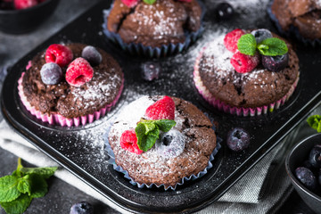 Chocolate orange muffins or cupcakes with berries.