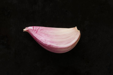 Single garlic clove on dark background, top view.