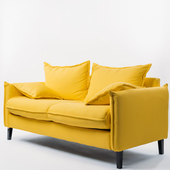 studio shot of yellow couch with pillows, on white