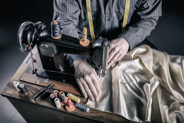 portrait and details of a tailor at work with an old and traditional sewing machine. manual and ancient work.