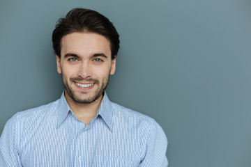 Facial expression. Portrait of a nice cheerful brunette man looking at you while showing his positive smile