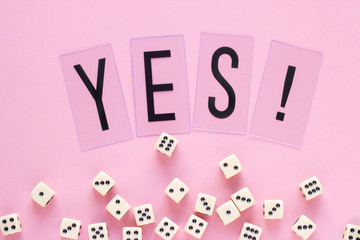 Gaming dice with word YES on pink background. Concept for games, game board, presentation, banners or web. Top view. Close-up.