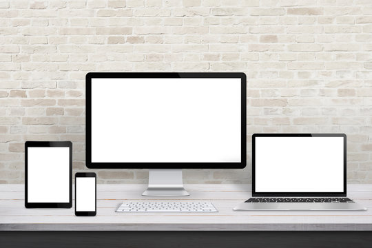 Multiple display devices for responsive web desing promotion. Modern office desk with brick wall in background.