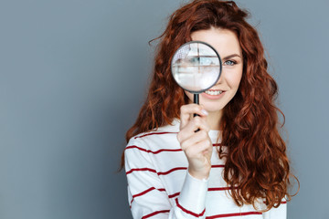 Laboratory equipment. Close up of magnifying glass being in hands of a cheerful smart red haired...