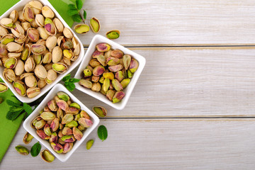 Pistachios on white wooden background with green napkin