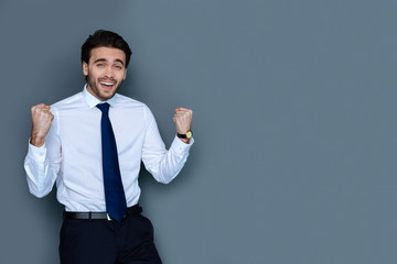 This is great. Joyful nice delighted man looking at you and smiling while celebrating his success