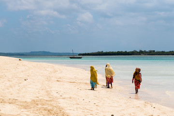 Тraditional African Muslim girls on walking along the beach of the ocean.Zanzibar