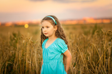Obraz premium Happy girl in wheat field on warm and sunny summer evening