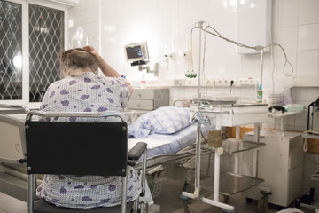 patient is an old woman sitting in the hospital room, intensive care unit