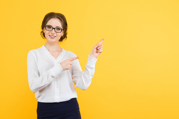 Portrait of confident beautiful young smiling happy business woman show on blankarea on yellow background