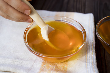 children's hand with the spoonful of honey on wooden background