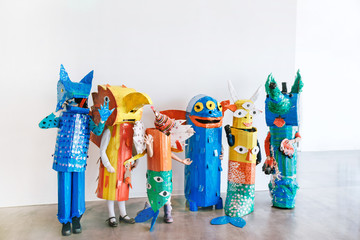 People in handmade colorful monsters costumes standing together in studio. © demphoto