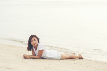 Fototapeta na wymiar Asian young girl lying down on the beach alone
