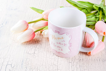 Mother's Day concept, greeting card background. Flowers tulips on a light concrete table, mug with inscription 