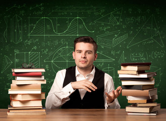A young passionate male teacher sitting at school desk, reading a book, with area algorythm...