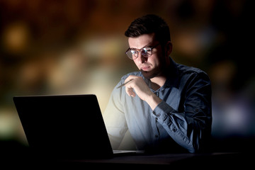 Young handsome businessman working late at night in the office