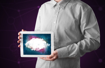 Fototapeta na wymiar Casual businessman holding tablet with cloud icon and purple background