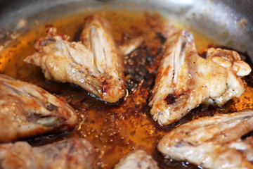 Chicken wings in sauce are fried in a pan. Cooking. Meat close-up