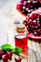 sliced pomegranate and extract in glass on wooden background