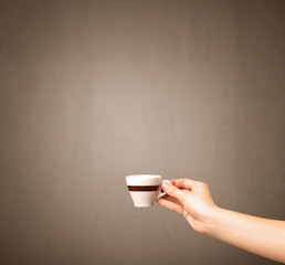 Young female hand holding coffee cup with brown background