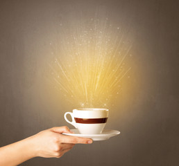 Young female hand holding coffee cup with a beam of light rising out of it 