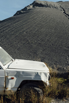 Old car close to a black gravel pile at a quarry