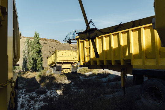 Old trailers abandoned close to a black gravel pile at a quarry