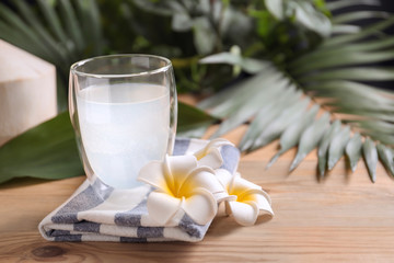 Glass with fresh coconut water on wooden table