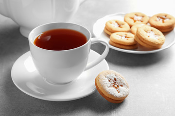 Tasty Linzer cookie with jam and cup of tea on table