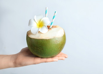 Female hand holding fresh green coconut with drinking straws on white background © New Africa