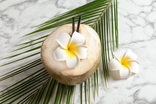 Fresh green coconut with flowers and palm leaf on table