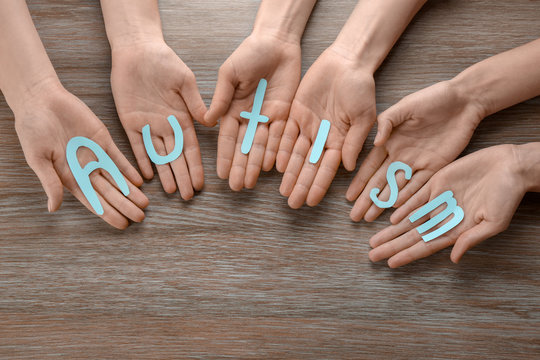 Group of people holding word "Autism" on wooden background