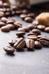 Black fried coffee beans on dark textured background