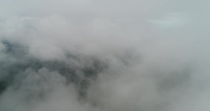 AERIAL. Flight above tropical island throught clouds and top view of mountains and forest. Thailand.