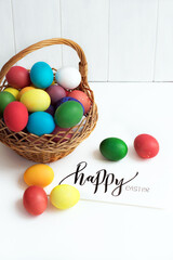 Easter card with colorful Easter eggs in a basket and calligraphic inscription "Happy Easter"