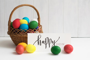 Easter card with colorful Easter eggs in a basket and calligraphic inscription "Happy Easter"