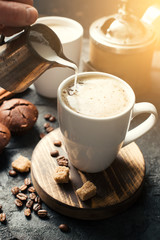 Black fried coffee beans in cafe with cookie and cake on dark textured background