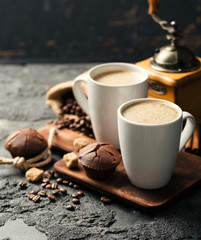 Black fried coffee beans in cafe with cookie and cake on dark textured background