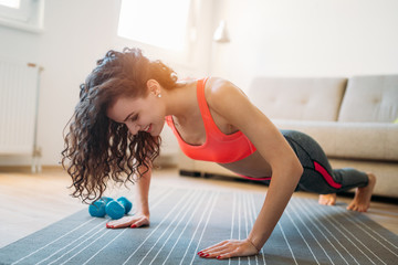 Young attractive sportswoman doing exercises at home