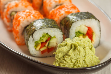 Close up wasabi and sushi rolls with vegetables, Uramaki California on the background. Japanese cuisine