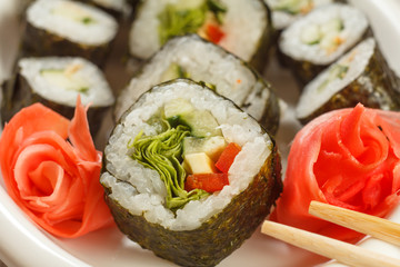 Close up Hosomaki with vegetables. Sushi roll with nori, rice, pieces of avocado, cucumber, red bell pepper and lettuce leaves