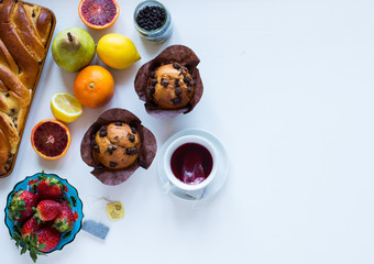 Breakfast with coffee and tea with different pastries and fruits on a white wooden table