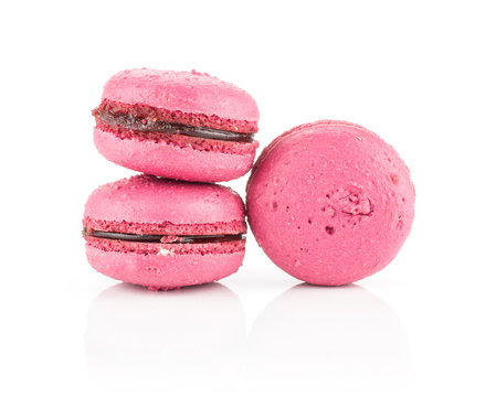 Three pink French macarons with raspberry jam isolated on white background.