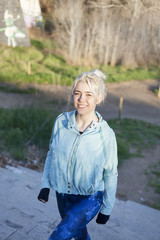 Active cheerful blonde pausing after a run in a park on a sunny day