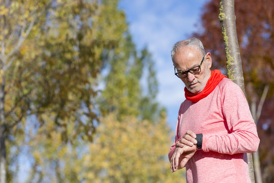 Senior runner man resting at the park while monitoring his exercise