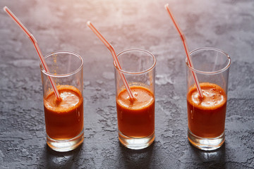 Glasses with freshly squeezed carrot juice on a dark stone background