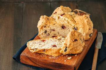Homemade cranberry raisin and walnut Irish soda bread on a wooden board. Wooden background.
