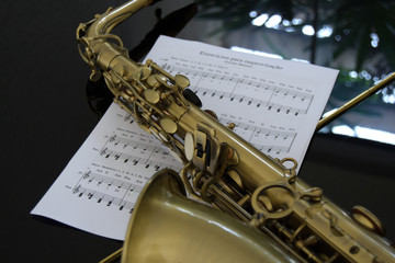 Saxofone e partitura sobre piano com reflexo do ambiente externo