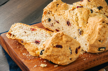 Homemade cranberry raisin and walnut Irish soda bread on a wooden board. Wooden background.