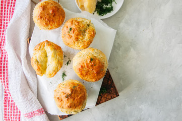 Savory double cheese muffins on a wooden board. White stone background.